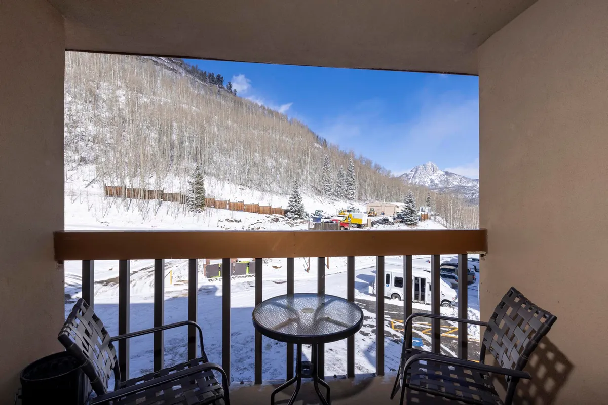 A tranquil outdoor seating area facing snow-covered mountains and aspen trees, ideal for unwinding with a hot drink after a day on the slopes. The serene view highlights the natural beauty of the Needles Mountain Range and the peacefulness of après-ski relaxation.